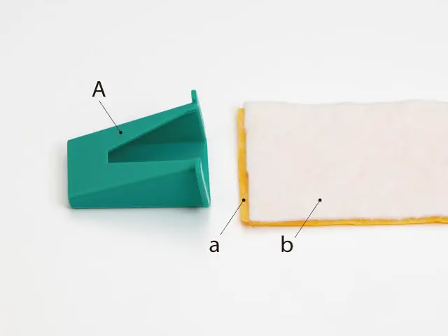 Teal angled plastic wedge labeled A placed next to a rectangular beige item with a yellow edge; labels a and b mark the small piece and the edge respectively, as in a diagram showing component parts.