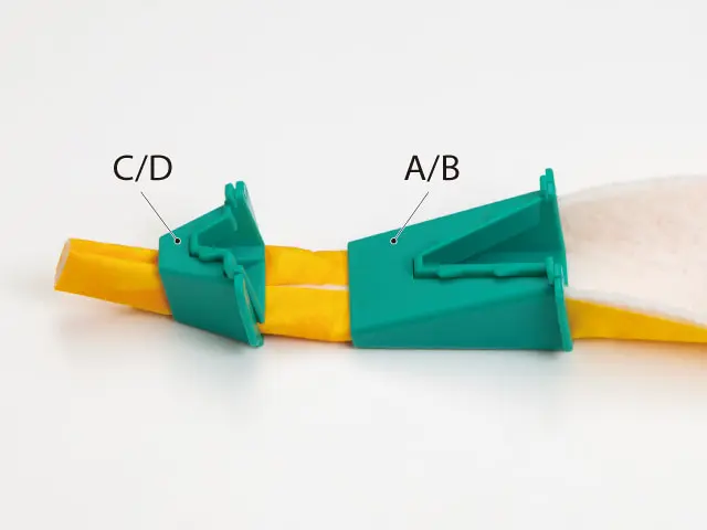Two teal plastic clamps labeled C/D and A/B grip a yellow strip in a line-up.