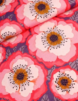 Close-up of pink and red poppy flowers with orange centers and black stamens on a purple background fabric.