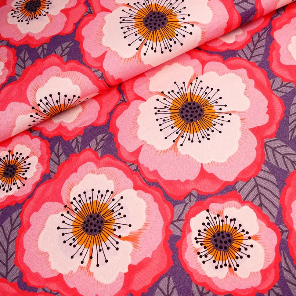 Close-up of pink and red poppy flowers with orange centers and black stamens on a purple background fabric.