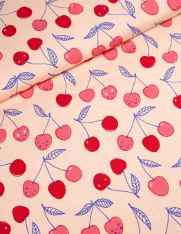 Beige fabric pattern with pink and red cherries and blue leaves scattered across, with gentle fold lines suggesting a draped textile.